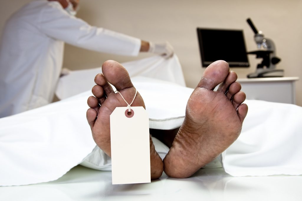 Mortician covering dead body in morgue